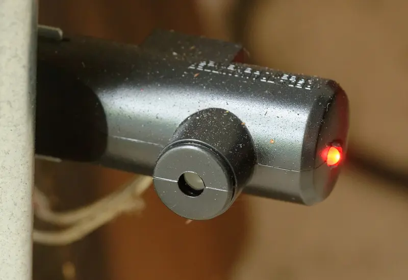 Photo-eye safety sensor mounted near the bottom of a garage door track