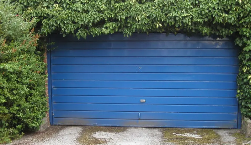 Weathered blue sectional garage door showing worn panels